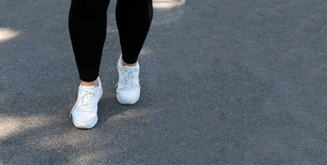 Close-up of legs in black leggings and white sneakers