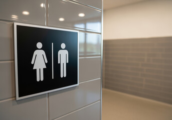 modern restroom entrance with wall mounted unisex sign inside a clean, contemporary public facility with neutral tile design