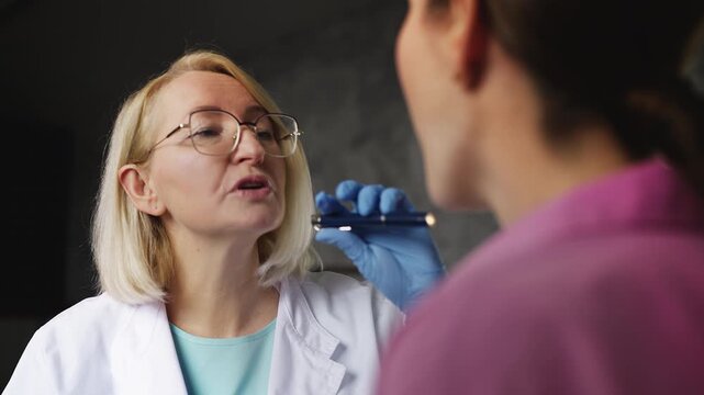 Otolaryngologist examining female patient's tonsils, infection symptoms check