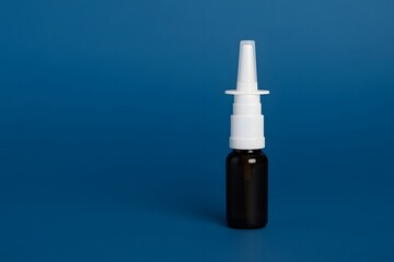 Close-up of nasal spray bottle with white nozzle on blue background, ideal for allergy relief, respiratory care, and naloxone medication visuals.