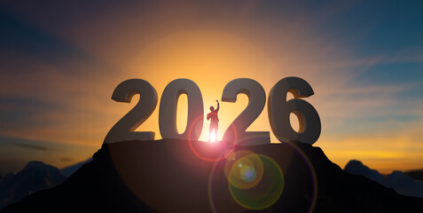 Silhouette businessman celebrating raising arms between word 2026 with sunset sky at Mountain and...