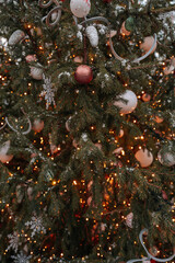 Christmas balls, beads and garlands light hanging on Christmas tree, festive background for winter holiday posters or postcards, indoor winter decor