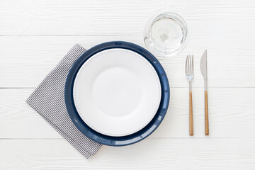 Table setting with empty plate and glass, cutlery and napkin, flat lay. Top view