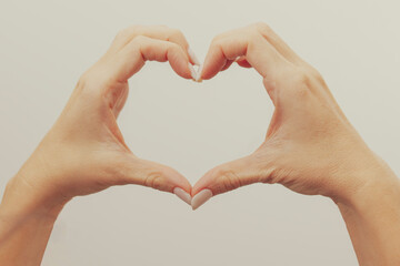 Obraz premium The hands of lovers making a sign heart shape isolated on white background.