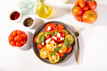 Sliced fresh tomato salad with basil leaves sprinkled with feta cheese	