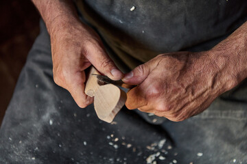 Close-up of a craftsman's hands carving wood with a sharp knife, shaping a wooden object, woodworking project, handmade craft, artisan skill, detailed handwork, artistic creation, small business