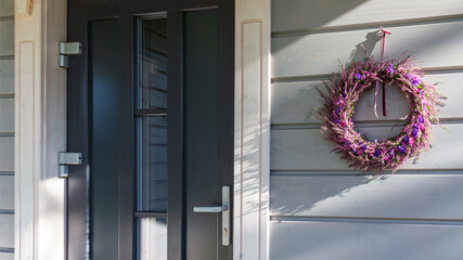 Decorative autumn wreath hanging on wooden wall near front door, seasonal holiday decoration with natural flowers, cozy home inspiration, thanksgiving, halloween mood, rustic house facade background