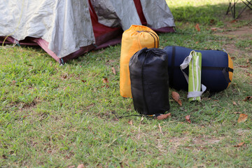 
Sleeping bags and camping gear on the grass next to a tent. Background with copy space