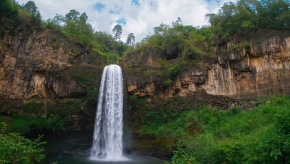 Naklejka premium Majestic waterfall cascading on a highland plateau, located inside a protected national park in Southeast Asia.