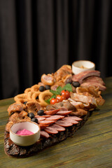 assorted meats on a wooden base with sauces and tomatoes
