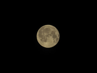 Full moon glowing softly against a deep black night sky, craters visible.