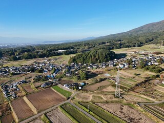 A rural area with a few houses and a large mountain in the background. The sky is clear and the sun is shining
