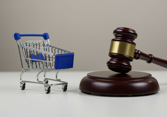 Miniature shopping cart next to a wooden judge's gavel symbolizing consumer rights, retail regulations, and legal protection in commerce