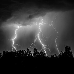 beautiful lightning during a thunderstorm at night in a forest that caused a fire, against a dark...