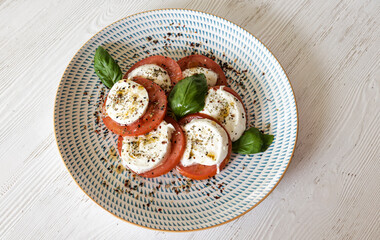 Caprese salad plating fresh mozzarella, tomato, and basil