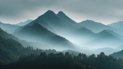Serene mountain peaks rise gracefully embraced by a gentle mist at dawn creating a tranquil scene.