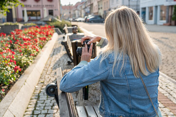 Young woman photographing park flowers with digital camera on sunny day