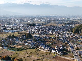 A city with a lot of houses and a few cars. The sky is cloudy and the sun is not very bright