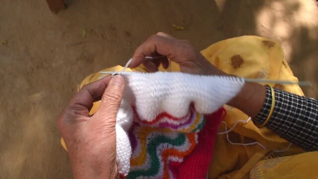 Elderly woman practicing her knitting hobby &ndash; colorful yarn and creative design. Concept of hobby, relaxation, creativity, and traditional handmade art practiced by senior citizens