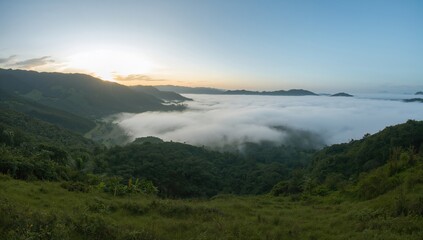 Serene morning scene of lush grassy hills and fog-filled expansive valley with faraway mountain tops