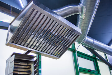 Stainless steel exhaust hood with grease trap close-up in a large industrial kitchen in the...