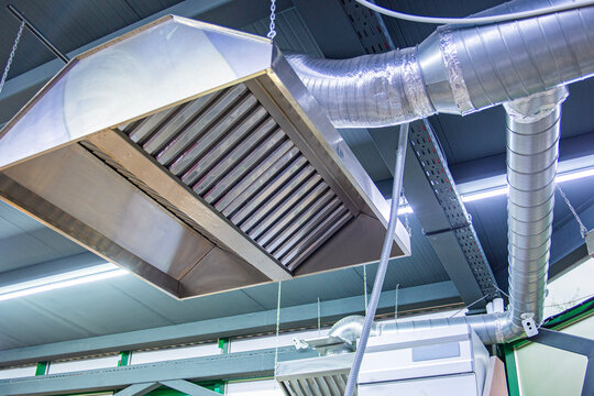 Stainless steel exhaust hood with grease trap close-up in a large industrial kitchen in the production of semi-finished products
