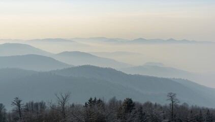 Obraz premium Mist-covered mountain layers extending into the horizon, seen from a nearby peak