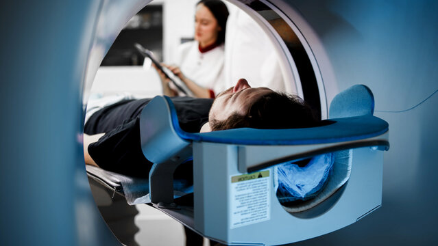 Patient undergoing CT scan in modern medical facility, with technician monitoring process, showcasing advanced imaging technology and healthcare environment