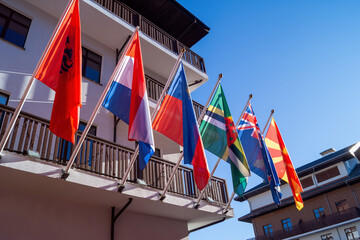 Colorful flags from various countries displayed in a bright blue sky at a hotel setting