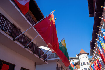 Flags from different countries waving under a bright blue sky in an outdoor setting