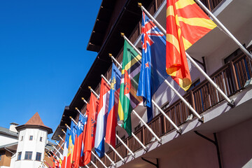 Various national flags displayed outside a building under a clear blue sky