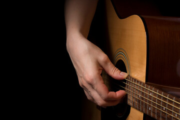 woman hand plays the guitar on black background, learning music. lifestyle