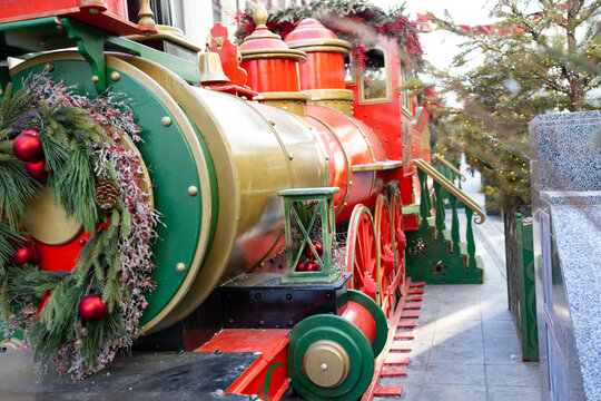 A colorful vintage train decorated for the New Year. Pine branches are visible in the foreground.