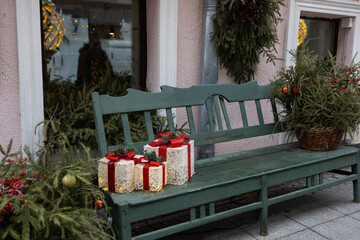 Decorative metal bench in front of a large Christmas tree decorated with red ornaments and garlands. Mnesto for relaxation.