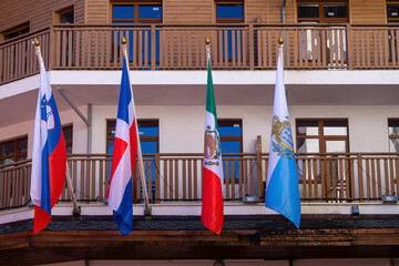 Flags of different countries displayed on a building in a lively urban setting