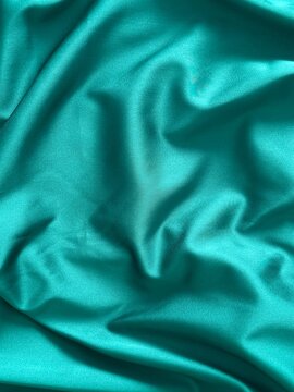 Smooth emerald green satin fabric with elegant folds and soft reflections, creating a luxurious and silky texture that shines beautifully under light, perfect for fashion, design, or interior inspirat