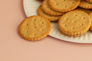 Fresh crackers on a white plate on a pink background close-up, soft focus, selective focus.