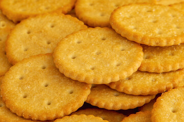 Yellow crackers stacked with salt grains on them, extreme close-up.