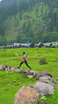 Defocused Indian man running in front of the Himalayan mountain ranges covered with clouds during the monsoon season near Udaipur in Pattan Valley, Lahaul, Himachal Pradesh, India.