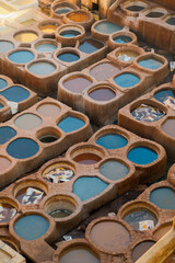 Close-up of traditional tannery in Fes, showing vivid dyed water and leather sheets soaking in the pits. The raw textures highlight Morocco’s historic leather-making process.
