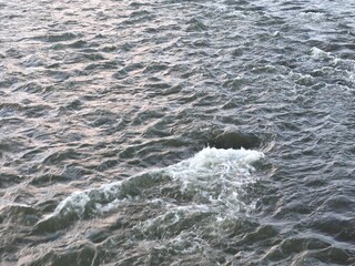 The water is choppy and the sky is pink. The water is dark blue and the sky is pink