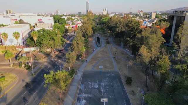 Aerial backward view of Lazaro Cardenas linear park with dry grass and tree-lined paths