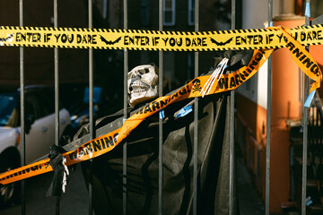 Halloween decorations display a skeleton behind caution tape in an urban setting at twilight
