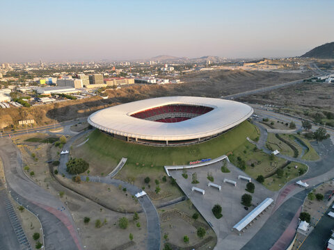 Guadalajara, Mexico - March 28 2024: Aerial drone view of Akron Stadium in Jalisco, Mexico. Modern architecture, white roof, green landscape. Urban area and hills