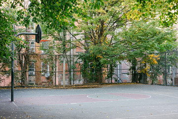 Naklejka premium Basketball court surrounded by trees in an urban neighborhood during autumn