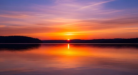 Naklejka premium Vibrant Sunset Reflection on Calm Lake Water with Distant Silhouette of Forest Hills Landscape Scenery Creates a Colorful Display Nature Outdoors Evening Sky Dusk Calm Beauty Scenery