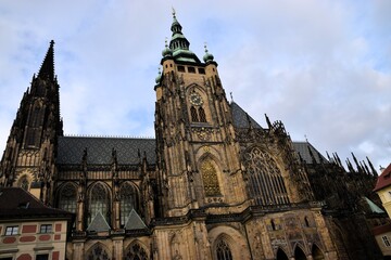 Low-angle detail of the southern facade of St. Vitus Cathedral in Prague, Czech Republic, highlighting the intricate Gothic architecture, spires, and the rich mosaic of the Golden Gate 