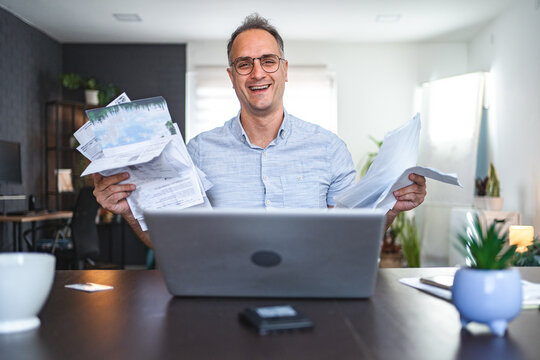 Middle aged Caucasian man working with a lot of paperwork at home