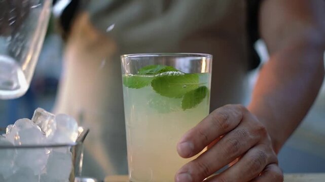 Street vendor pours refreshing ash gourd juice into a glass filled with ice and mint leaves, early evening street light glows softly, evoking tropical freshness and local beverage culture.