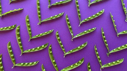 Fresh green pea pods arranged artistically on vibrant purple background, showcasing natural...